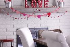 a chic and simple Valentine mantel with marquee letters, white trees with hearts, a greenery wreath and garlands