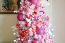 a colorful and whimsy Valentine tree in pink with white pompoms, pink and red ornaments and heart decor