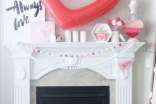 a cool Valentine fireplace with a pompom garland, candles, hearts and a large balloon heart