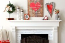 a cute Valentine mantel with a wooden sign, a plaque heart, black candles, red blooms in a churn
