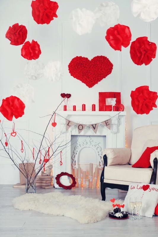 a faux fireplace with candles, a frame, red candles on the mantel and lots of white and red pompoms