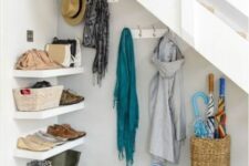 a functional under stairs mudroom with shelves, a basket with umbrellas, some hooks is a practical and cool idea