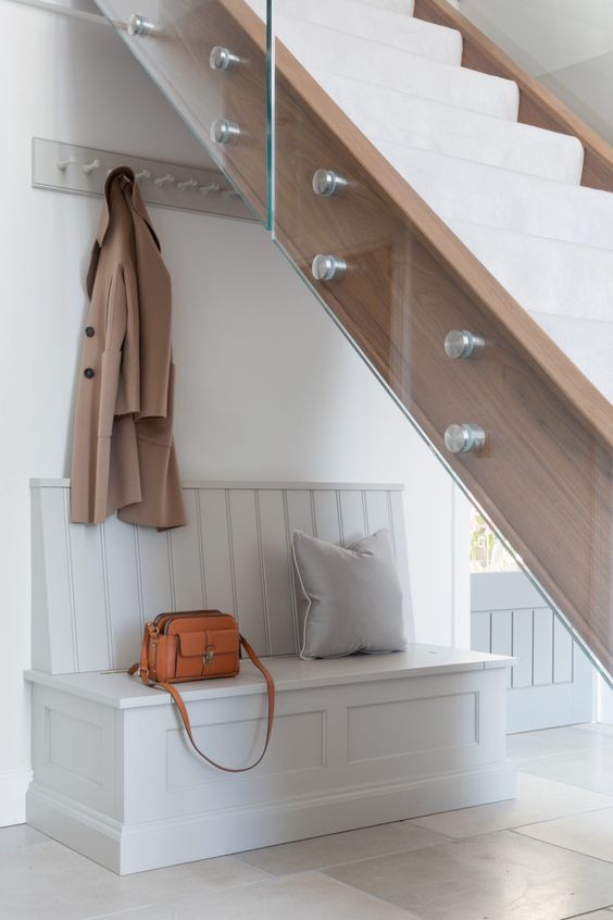 a minimal under stairs mudroom with a rack and a built-in storage bench is a cool idea for a small space and if you don't need much storage space