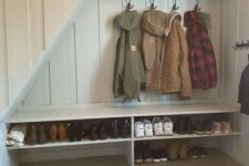 a small under stairs mudroom with built-in shelves, racks and baskets for storage plus a jute rug is a cool idea