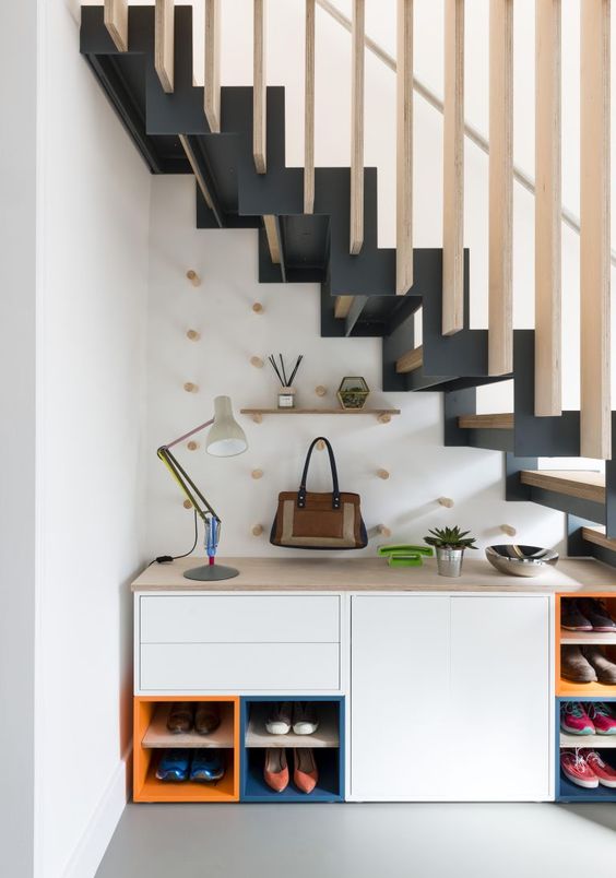 a storage unit for shoes, hooks and a table lamp, potted plants are a great combo for a staircase