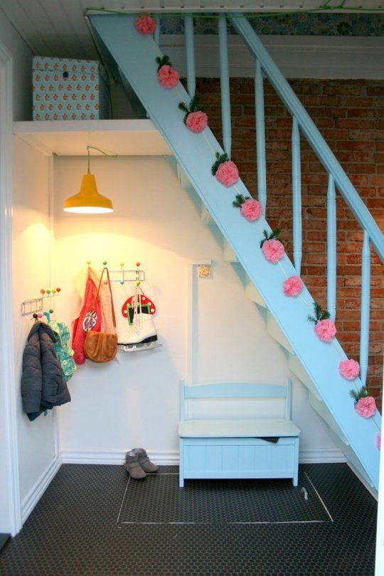 a tiny mudroom udner the stairs with a small bench, racks and a yellow pendant lamp is a fun and cool solution