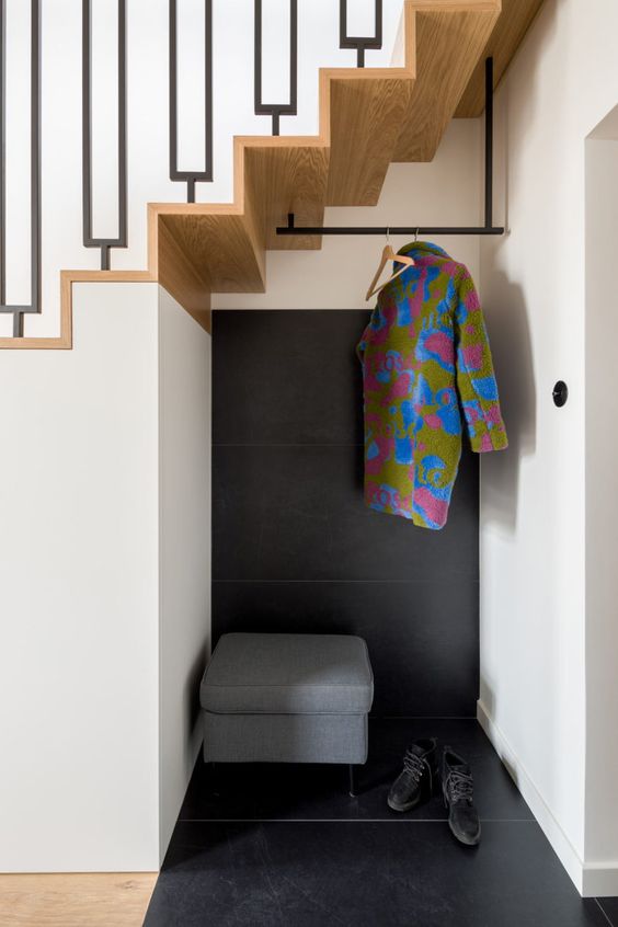 a tiny under stairs mudroom with a storage pouf, a rack and nothing else is a perfect solution for a small space