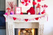 a whimsical Valentine mantel with fluffy colorful hearts, red candle lanterns and red hearts on the wall