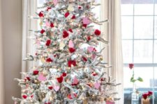 a whimsy snowy Valentine tree with lights, red and pink roses and hearts and some heart ornaments