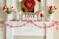 an elegant Valentine fireplace and mantel, with pink and red tulips, a heart wreath and a heart garland