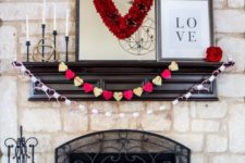 an elegant Valentine mantel with a red heart, paper heart garlands and red blooms