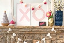 cute Valentine styling with a white heart garland with tassels, XO signs, colorful tassel garlands and blooms