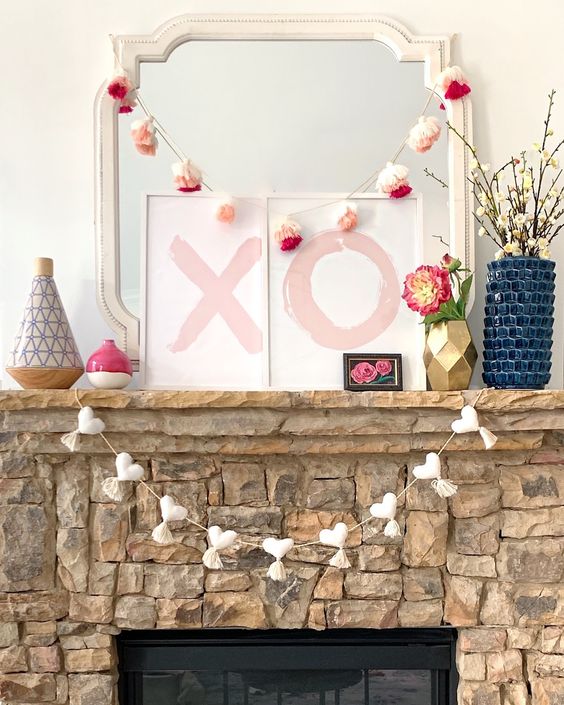 cute Valentine styling with a white heart garland with tassels, XO signs, colorful tassel garlands and blooms