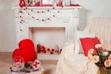 cute and romantic Valentine fireplace styling with heart garlands, candles, a sign, a red lamp and red heart pillows