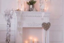 neutral faux fireplace decor with white paper hearts, candles on the mante and inside the fireplace and white tulips