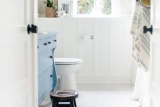 07 a cozy traditional bathroom with a white penny tile floor, wainscoting and a blue dresser looks cool