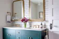 08 an eye-catchy bathroom with white subway tiles, a teal vanity and brass mirrors and other touches for a chic look