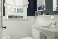 12 white subway tiles with white grout and navy walls create a cool contrast in the small bathroom