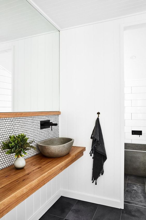 a contemporary bathroom with white penny tiles and black grout, a floating wooden vanity and a concrete sink