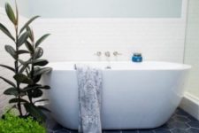 18 navy hex tiles on the floor ad white tiles on the walls create a bold and catchy combo, greenery to refresh the space