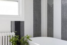 24 a bathtub backsplash made of black and white penny tiles clad in stripes and fresh greenery to enliven the space