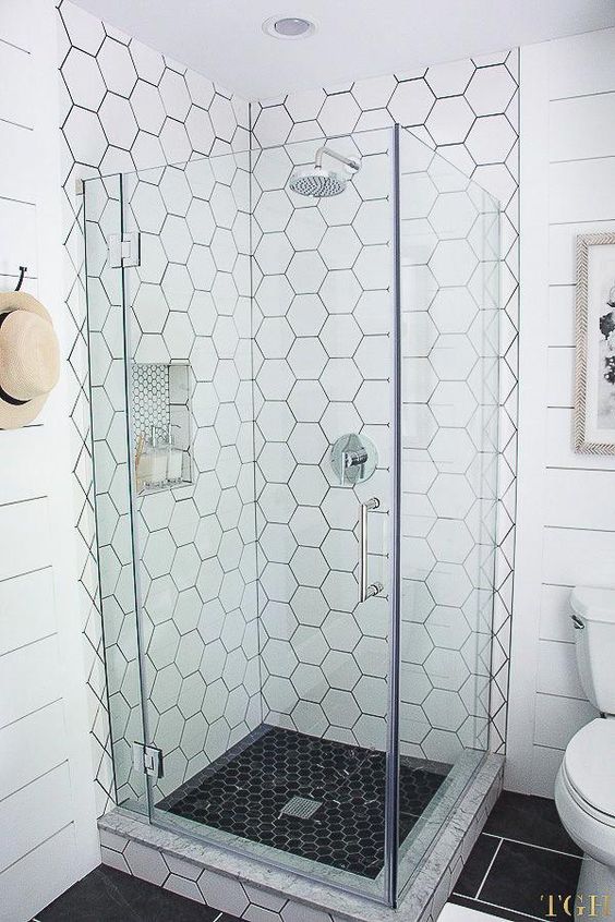 a neutral shower done with white hex tiles on the walls and black mini hex tiles on the floor