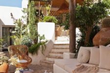 Mediterranean terrace with tree stump stools, rattan chairs, greenery and cacti plus pendant lamps