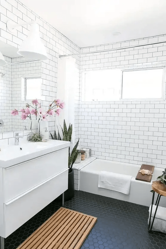 a bathroom clad with subway tiles accented with black grout and black hexagon tiles on the floor is trendy