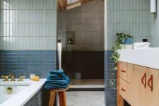 a bathroom with pale blue and navy skinny tiles and white hexagon ones, with a large shower space and a tub clad with tiles