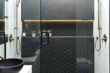 a black and white bathroom with hexagon tiles in the shower space and brass touches for more elegance