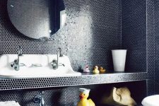 a black modern bathroom clad with penny tiles, witha vanity done with these tiles, a vintage sink, a round mirror and white stools