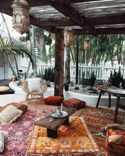 a boho Moroccan terrace with wooden and rattan furniture, colorful boho rugs and Moroccan lanterns