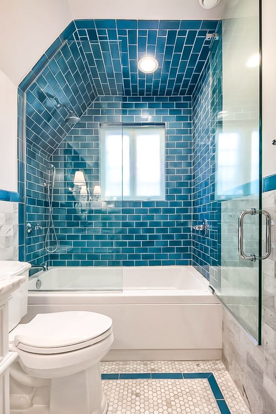 a bold bathroom done with blue subway and penny tiles, white appliances and a window feels very seaside-like
