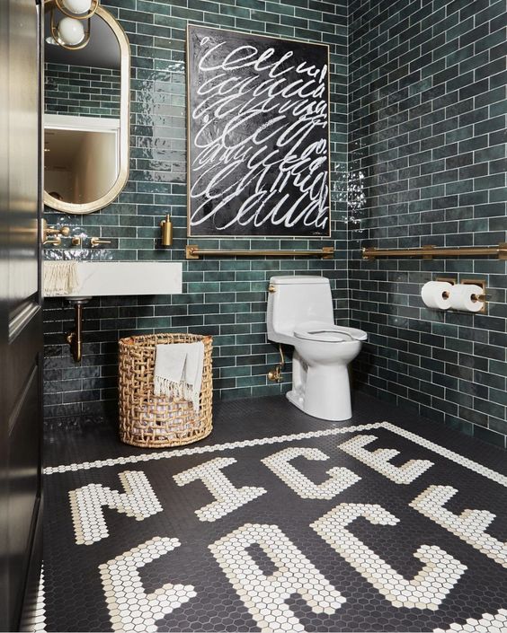 a bold powder room done with green subway and black and white penny tiles, a sink, brass fixtures and a basket is wow