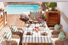 a bright Mediterranean terrace with rattan chairs, a wooden table and planters, printed textiles and bright blooms