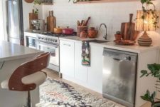 a bright boho kitchen with printed rugs, potted greenery, wooden tableware and warm colored porcelain