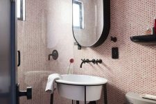 a bright red and pink bathroom clad with penny tiles, a shower space, a sink, a mirror cabinet and black fixtures