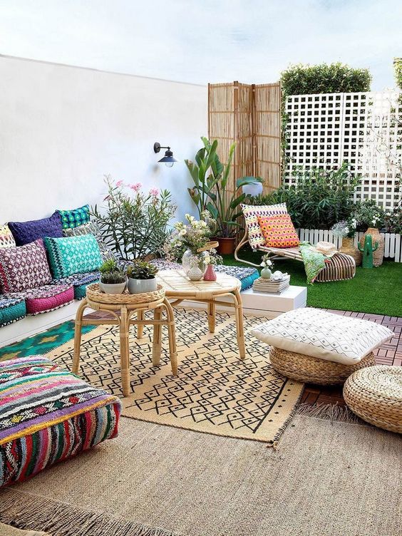 a bright summer terrace with Mediterranean and Moroccan influences, bright printed textiles and potted blooms plus jute ottomans