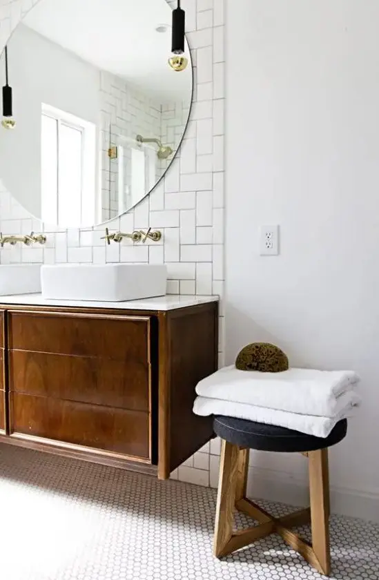 A chic mid century modern bathroom in neutrals, with subway and hex tiles, a dark stained vanity and stool and pendant lamps