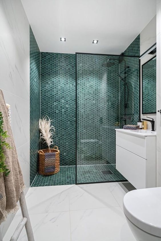 a chic modern bathroom with a shower space done with green hex tiles, white large scale ones and a floating vanity