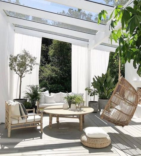a chic tropical terrace with a hanging chair, rattan furniture, potted greenery is classics
