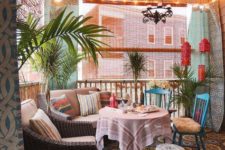 a colorful boho chic terrace with a printed rug, striped pillows, carved tables, potted greenery and lanterns