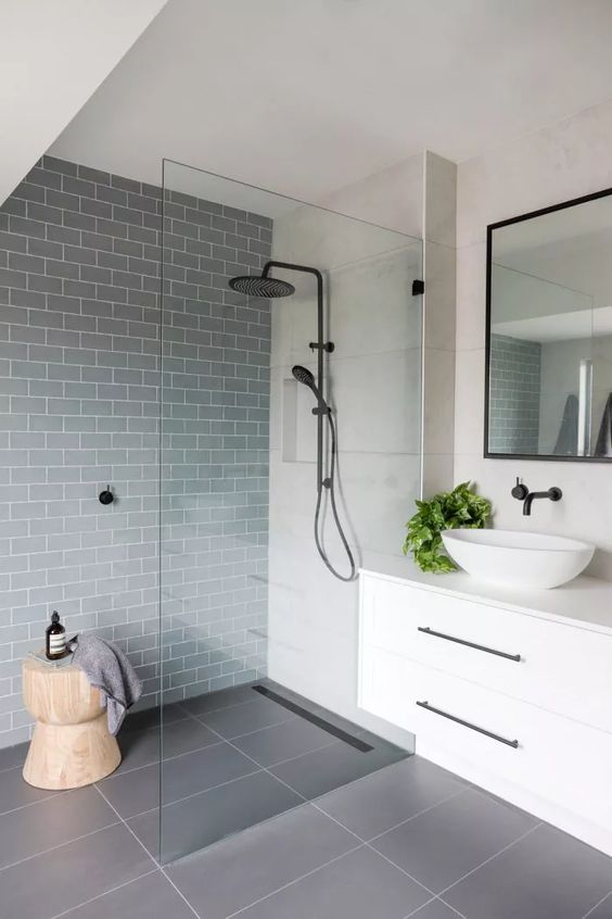 a contemporary bathroom done with a grey subway tile accent wall, a shower space, a floating vanity, black fixtures