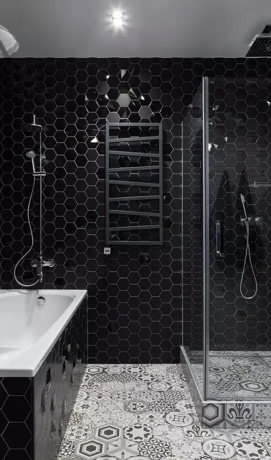 a contemporary bathroom with black hex tiles, a mosaic tile floor, a shower enclosed in glass and a black radiator