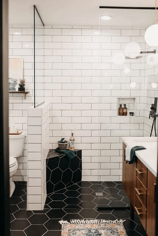 A contrasting mid century modern bathroom with white subway and black hex tiles, a rich stained vanity and touches of gold