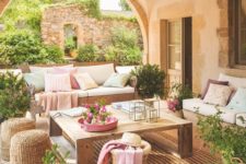 a cozy Mediterranean terrace with jute rugs and ottomans, wooden furniture, pastel textiles and potted greenery