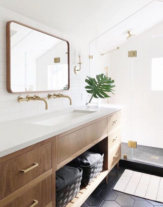 A gorgeous light filled mid century modern bathroom with windows, black hex tiles and skinny white ones, a wooden vanity and touches of gold