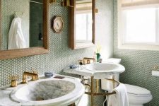 a grene bathroom clad with penny tiles, a neutral floor, free-standing sinks, mirror and gold and brass fixtures