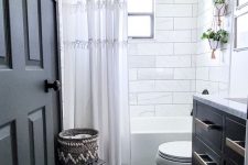 a grey and white bathroom with marble and hex tiles, a gra[hite grey vanity and a grey stool with a basket