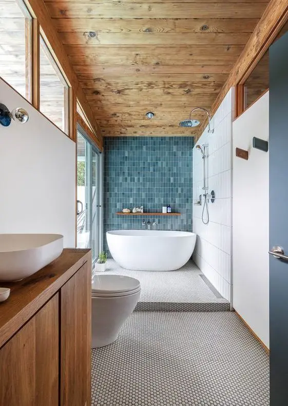 a large mid-century modern bathroom with a wooden ceiling, a penny tile floor and a blue accent wall, a stained vanity and white appliances